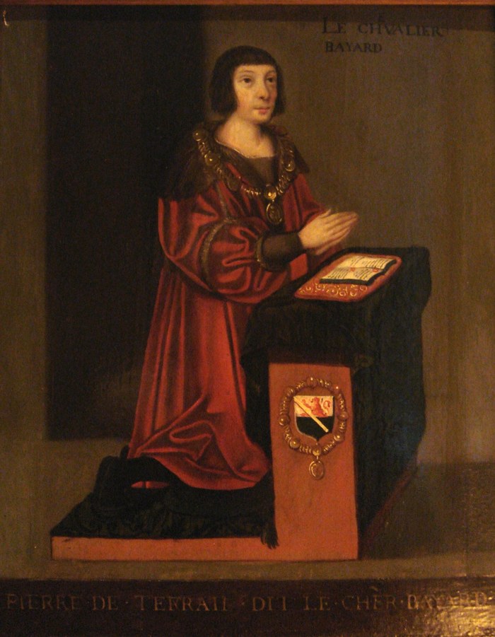 Portrait peint du chevalier Bayard agenouillé en prière, en robe rouge, devant un prie-Dieu portant ses armes